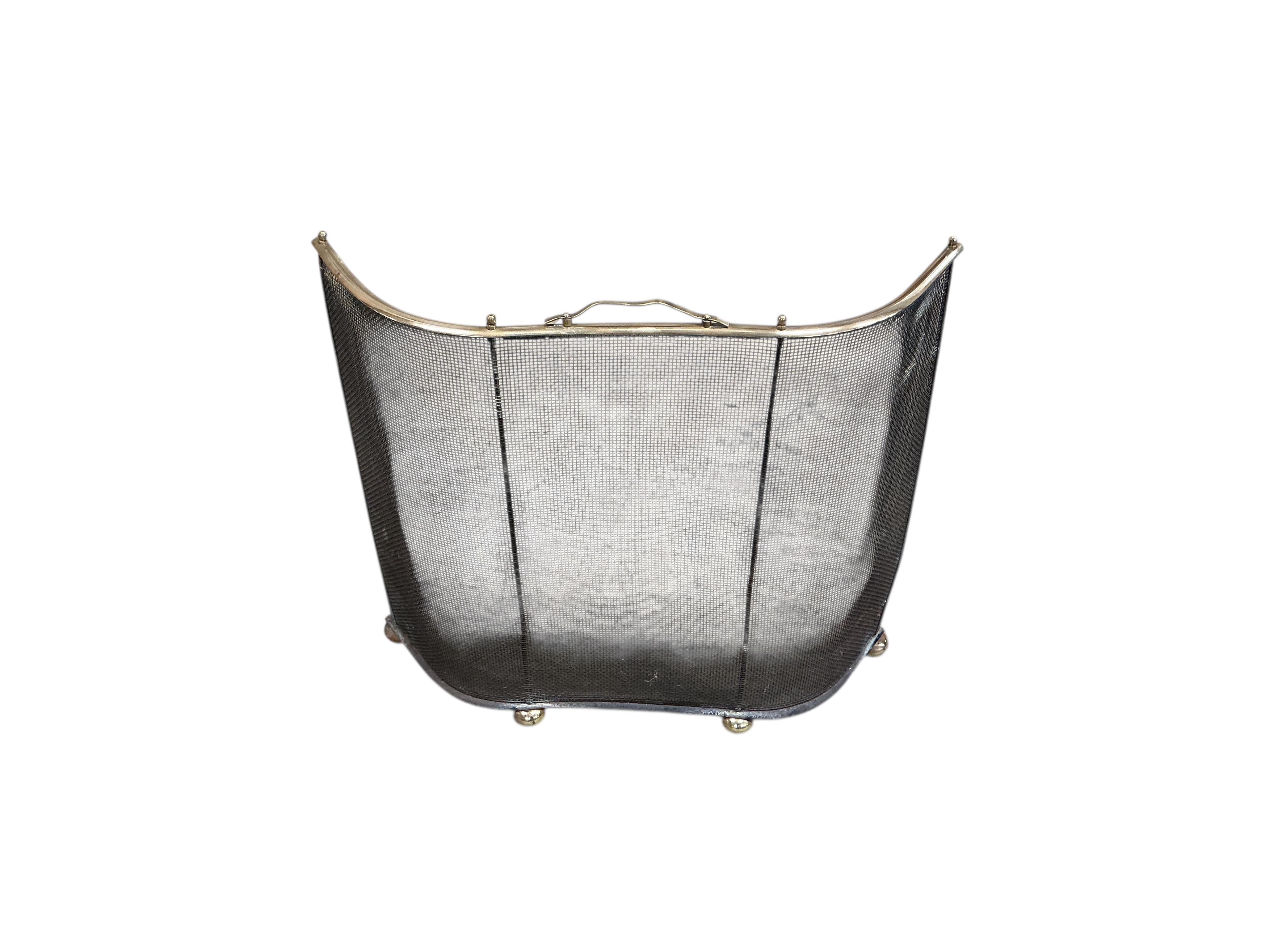 A pair of wrought iron and brass tipped fire dogs together with a black painted iron and wire mesh three fold spark guard and one other spark guard